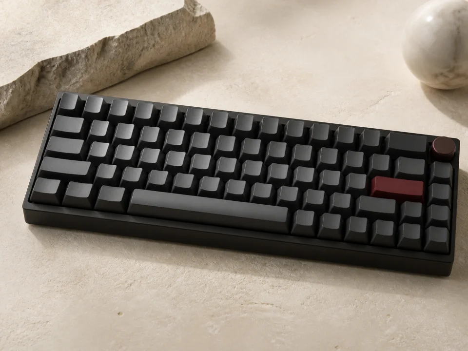 Compact custom mechanical keyboard on a warm stone surface